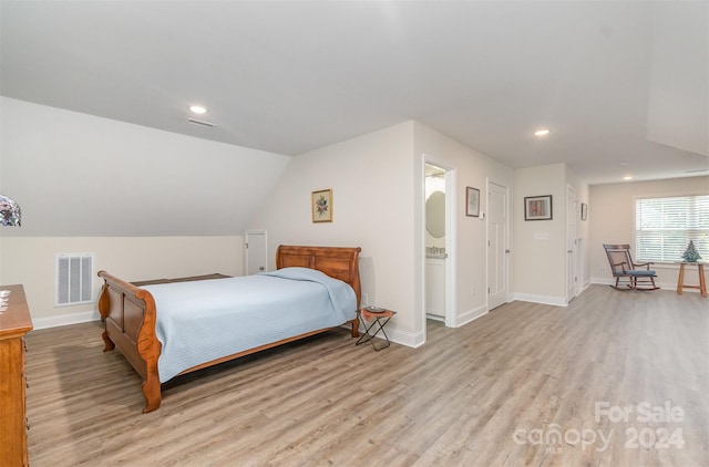 bedroom with lofted ceiling, light hardwood / wood-style flooring, and ensuite bath