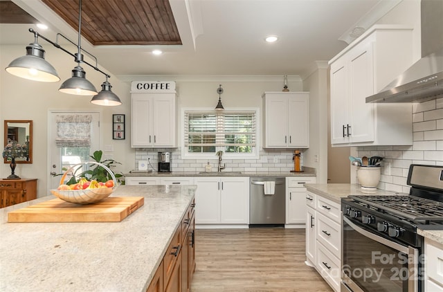 kitchen featuring appliances with stainless steel finishes, white cabinetry, wall chimney exhaust hood, and light stone countertops