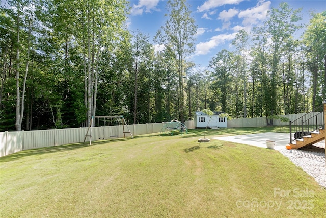 view of yard with a playground, a shed, an outdoor structure, and a fenced backyard