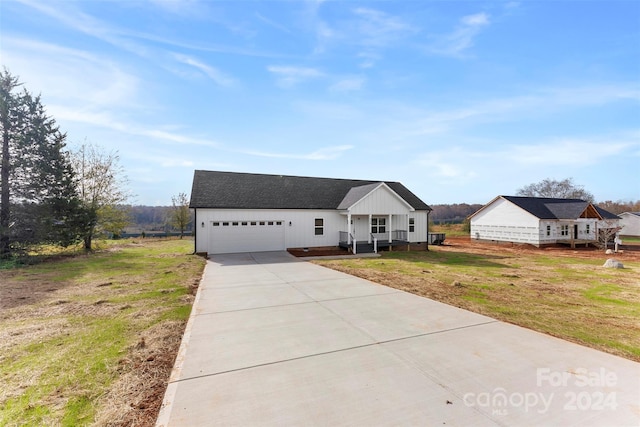 view of front of home with a front lawn, covered porch, and a garage