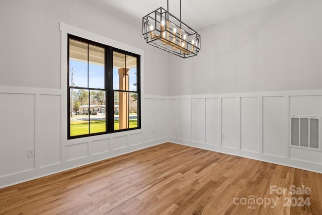 unfurnished dining area with light wood-type flooring and an inviting chandelier