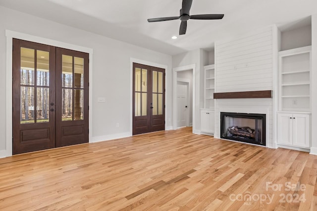 unfurnished living room featuring light hardwood / wood-style flooring, built in shelves, and french doors