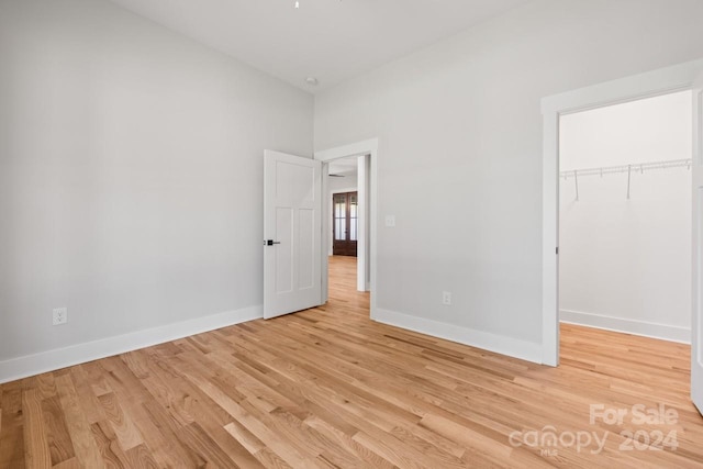 unfurnished bedroom with a spacious closet, a closet, and light wood-type flooring