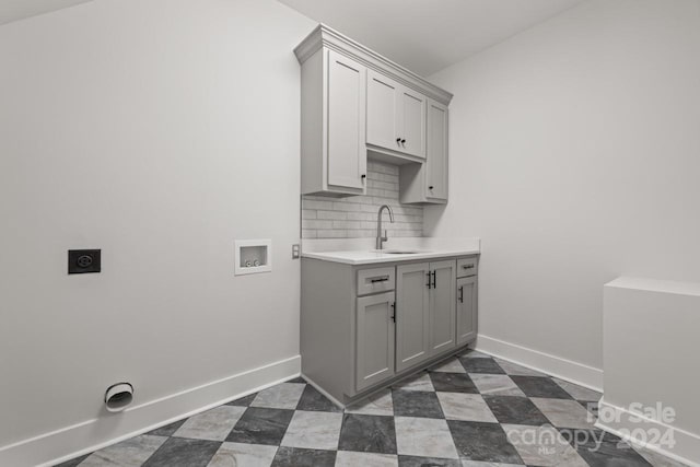 clothes washing area featuring dark tile patterned floors, hookup for a washing machine, sink, cabinets, and electric dryer hookup