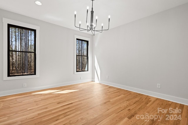 empty room with an inviting chandelier and light hardwood / wood-style flooring