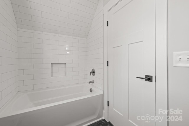 bathroom featuring lofted ceiling and tiled shower / bath