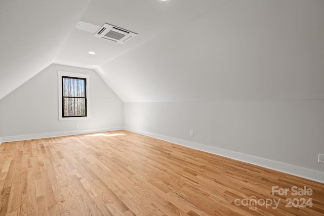 bonus room with light wood-type flooring and vaulted ceiling