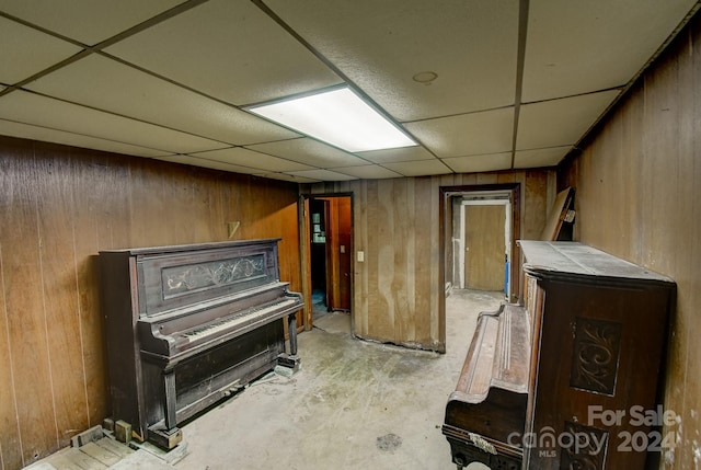 basement with wood walls and a paneled ceiling