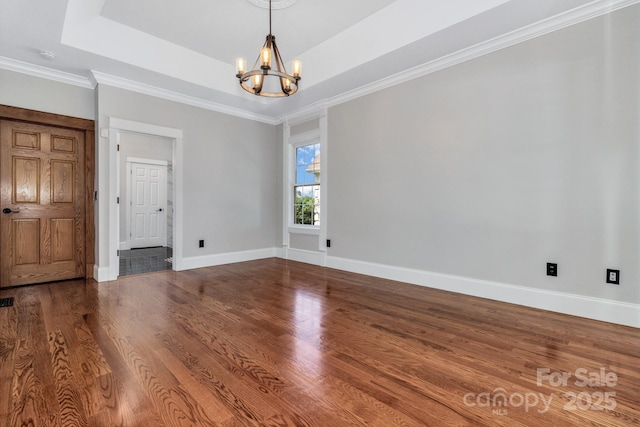 spare room featuring wood-type flooring, crown molding, a chandelier, and a tray ceiling