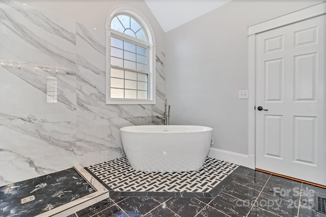 bathroom featuring a tub to relax in, lofted ceiling, and plenty of natural light