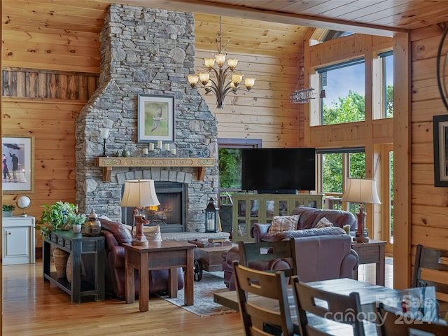 living room with wood walls, wooden ceiling, a fireplace, hardwood / wood-style floors, and a chandelier