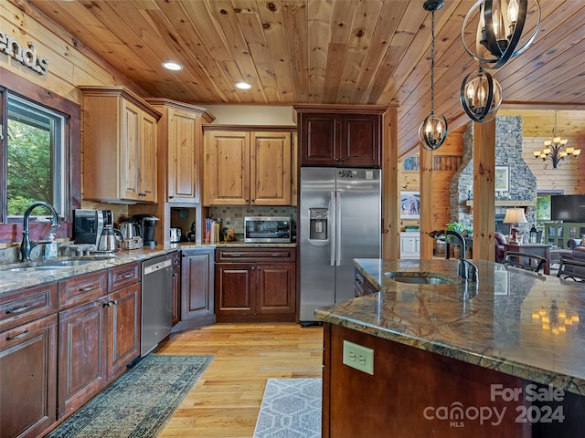 kitchen with dark stone countertops, an inviting chandelier, sink, hanging light fixtures, and appliances with stainless steel finishes