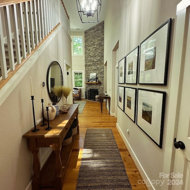 hallway with wood-type flooring, a chandelier, and a towering ceiling