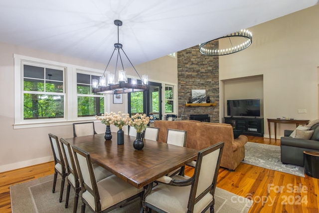 dining space featuring light wood-type flooring, a fireplace, and an inviting chandelier