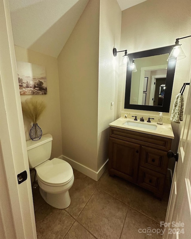 bathroom with vanity, toilet, vaulted ceiling, and tile patterned floors