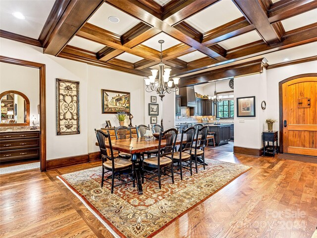 dining space featuring coffered ceiling, light hardwood / wood-style flooring, beamed ceiling, and a chandelier