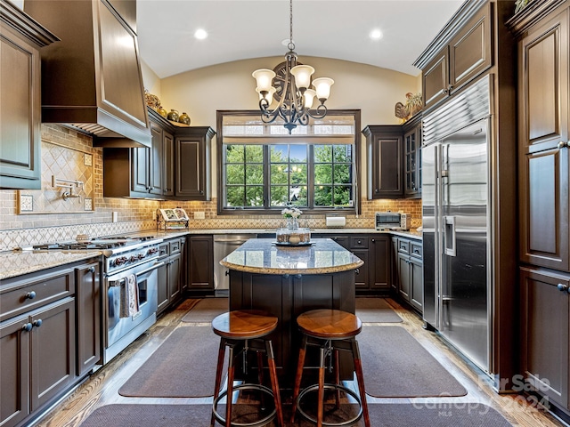 kitchen with custom exhaust hood, light stone counters, high quality appliances, tasteful backsplash, and lofted ceiling