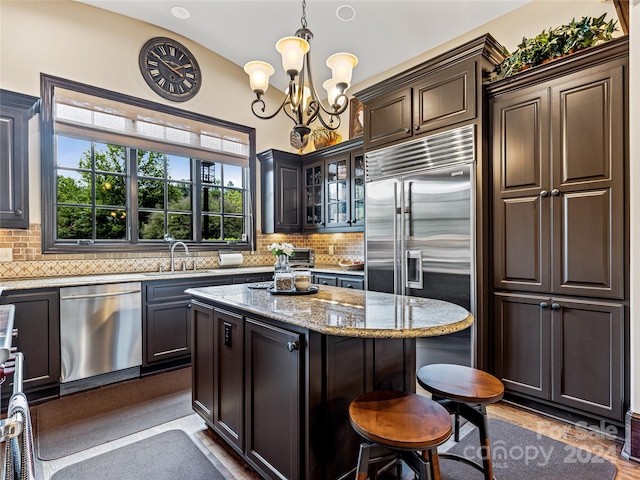 kitchen featuring backsplash, dishwasher, decorative light fixtures, and light stone countertops