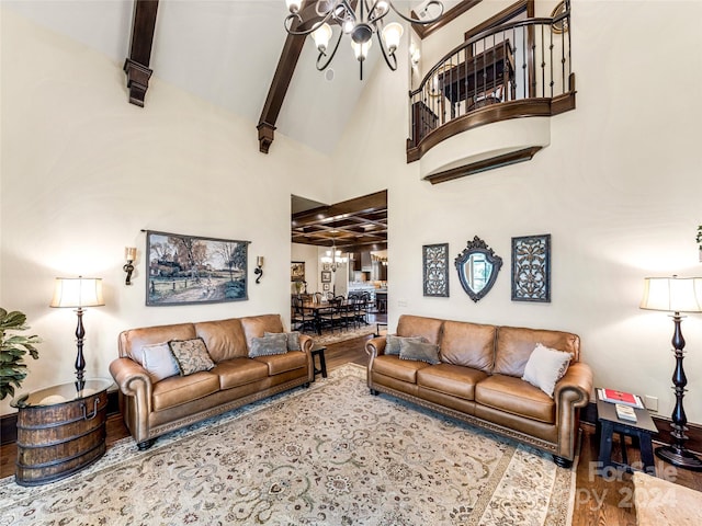 living room with a towering ceiling, light wood-type flooring, a notable chandelier, and beam ceiling