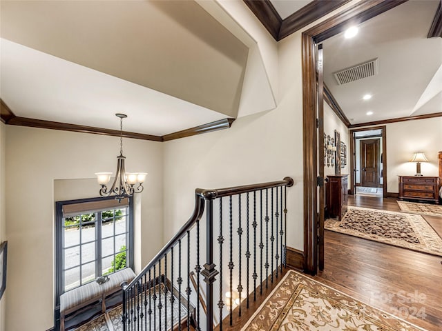 hallway featuring hardwood / wood-style flooring, crown molding, and a notable chandelier