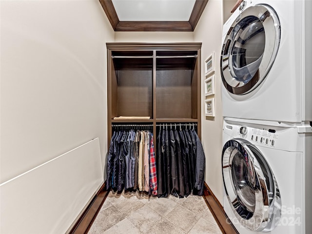 clothes washing area featuring stacked washer / drying machine, ornamental molding, and light tile patterned floors