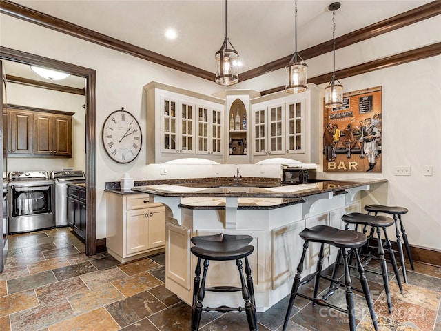 kitchen with dark tile patterned flooring, a breakfast bar area, hanging light fixtures, and separate washer and dryer