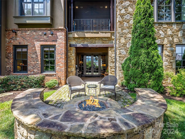 view of patio featuring a balcony, an outdoor fire pit, and french doors