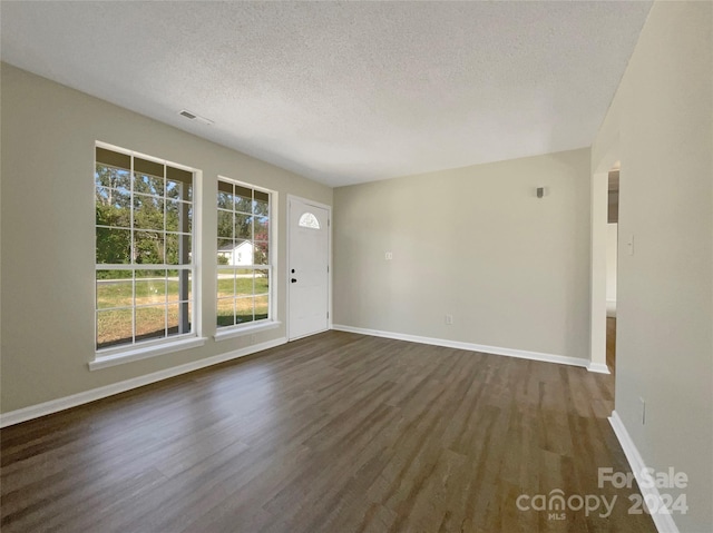 interior space with dark wood-style floors, visible vents, a textured ceiling, and baseboards