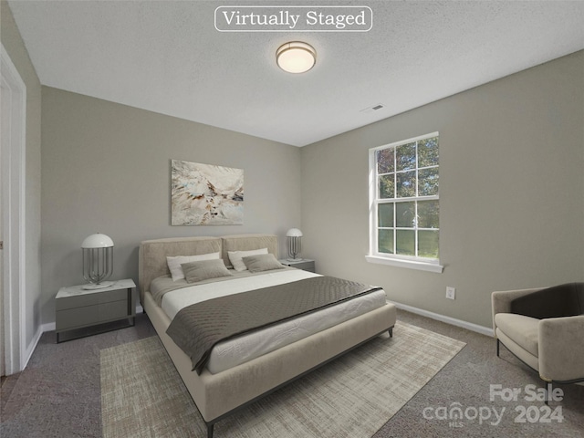 carpeted bedroom featuring visible vents, a textured ceiling, and baseboards