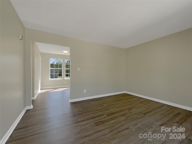 unfurnished room featuring dark wood-style floors and baseboards