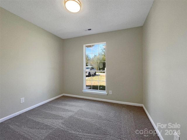 spare room featuring carpet floors, visible vents, a textured ceiling, and baseboards