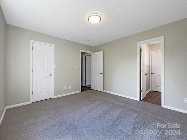 unfurnished bedroom featuring dark carpet and baseboards