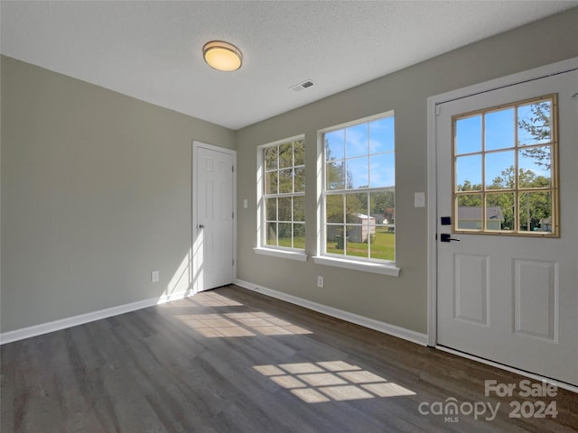 entryway with dark wood-type flooring, visible vents, and baseboards