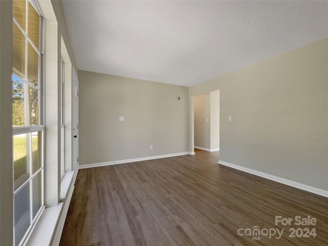 empty room with baseboards and dark wood finished floors