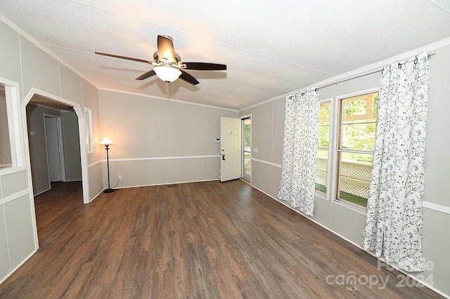 unfurnished room featuring ornamental molding, arched walkways, and wood finished floors