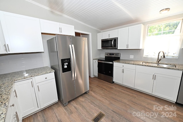 kitchen with tasteful backsplash, lofted ceiling, appliances with stainless steel finishes, wood finished floors, and a sink