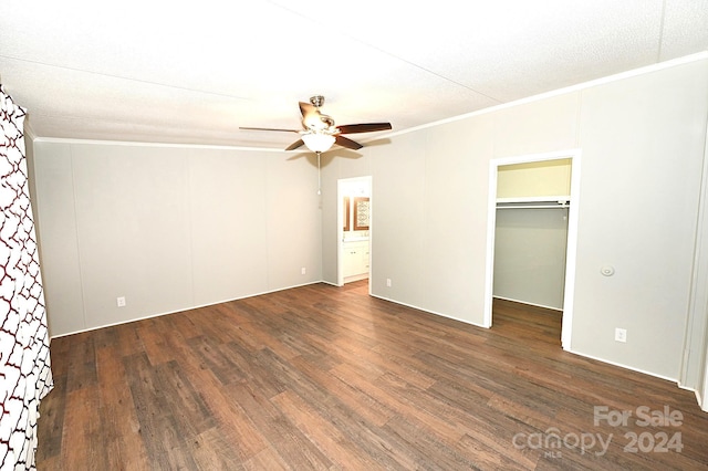 unfurnished bedroom featuring connected bathroom, wood finished floors, a ceiling fan, a spacious closet, and ornamental molding