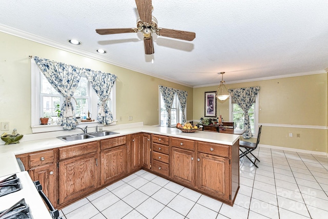 kitchen with kitchen peninsula, crown molding, ceiling fan, decorative light fixtures, and sink