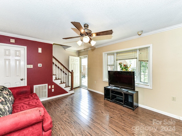 living room featuring ornamental molding, ceiling fan, dark wood-type flooring, and a textured ceiling