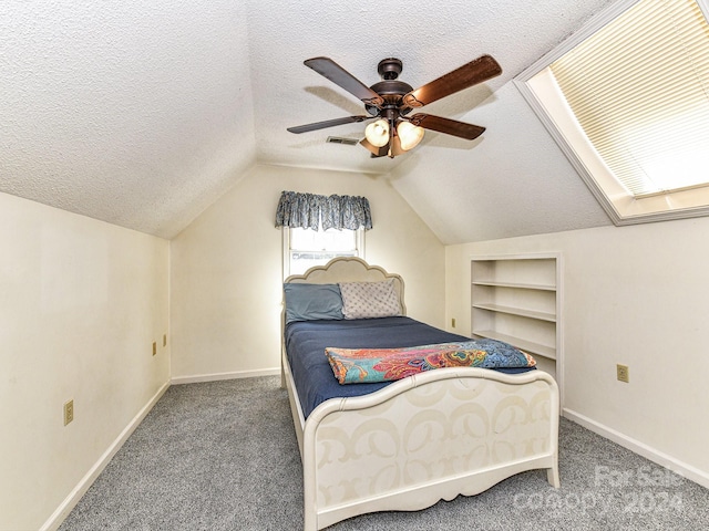 carpeted bedroom featuring ceiling fan, a textured ceiling, and lofted ceiling with skylight