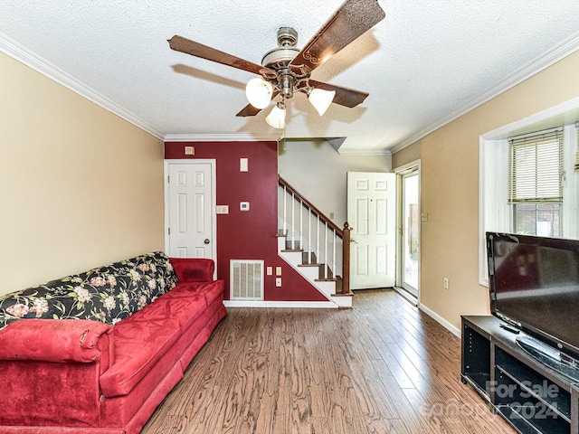 living room featuring ceiling fan, hardwood / wood-style flooring, crown molding, and a textured ceiling