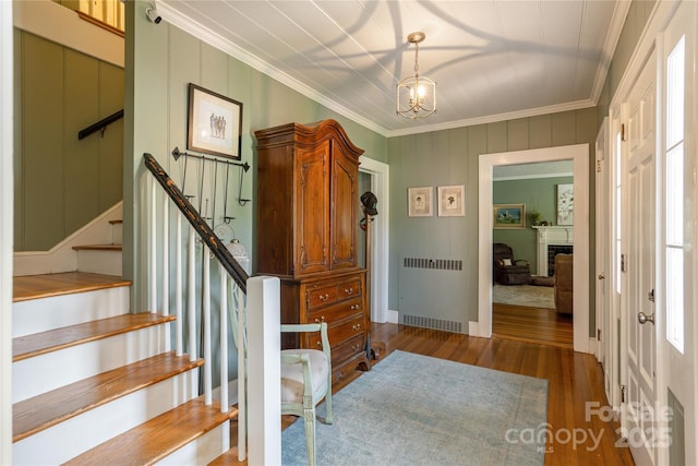 entrance foyer with dark hardwood / wood-style flooring, radiator, a notable chandelier, and ornamental molding