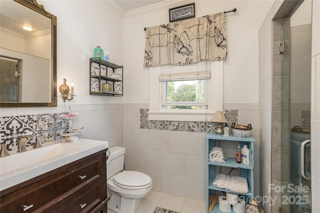 bathroom featuring tile walls, vanity, toilet, a shower with door, and crown molding