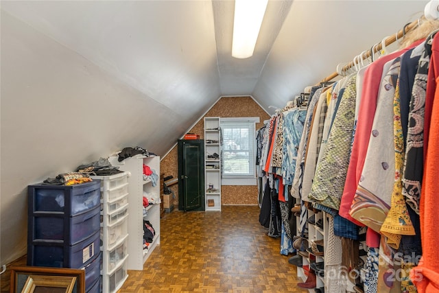 walk in closet with vaulted ceiling and dark parquet floors