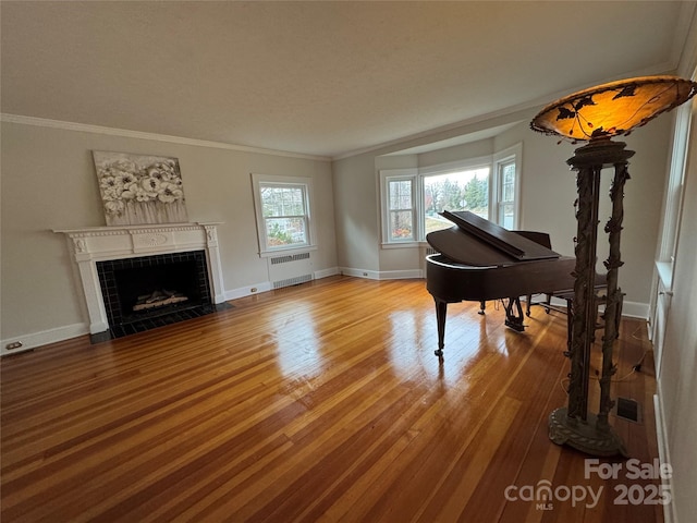 misc room with ornamental molding, wood-type flooring, a fireplace, and radiator