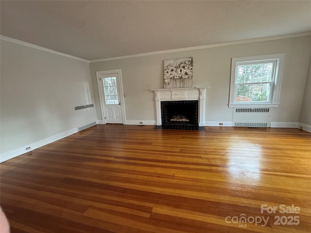 unfurnished living room featuring ornamental molding, radiator heating unit, and wood-type flooring