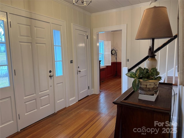 foyer entrance with crown molding and wood-type flooring