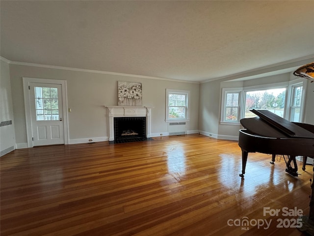 interior space featuring ornamental molding, radiator heating unit, and light wood-type flooring