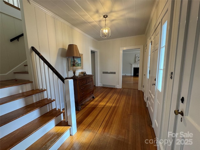 foyer with wood-type flooring, radiator, and crown molding