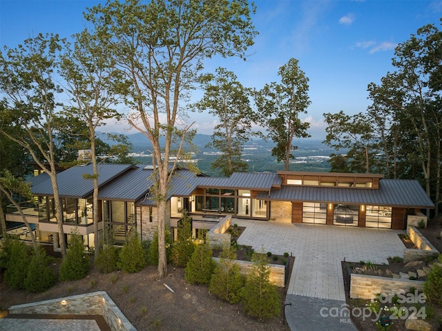 rear view of house featuring decorative driveway, metal roof, a mountain view, and a standing seam roof